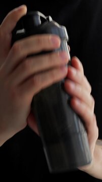Sports shaker for mixing protein and gainer in it. Sports nutrition and food supplements.
A man shakes a sports bottle with protein after strength training