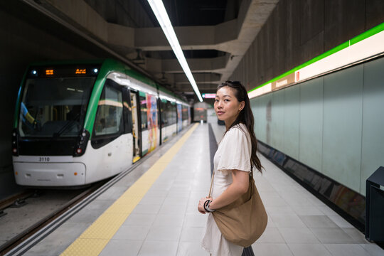 Asian woman waiting at metro station platform