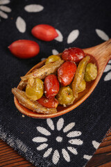 Deep fried small fish with vegetables and peanuts in wooden spoon - healthy snack food concept