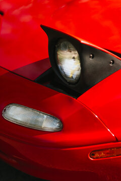 Close-up of pop-up headlight on classic red convertible car