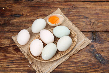 Fresh Farm Eggs in Rustic Wicker Basket on Wooden Background with Orange Yolk