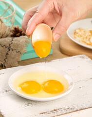 Fresh Farm Egg Being Cracked with Golden Yolk Dripping into Bowl for Cooking Preparation