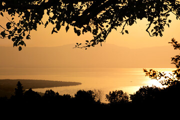 Coucher de soleil sur le lac Léman or brillant depuis les montagnes de la rive française avec vue sur sur la silhouette de la rive suisse. 