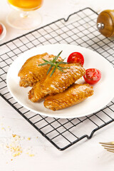 Golden Salt-Baked Chicken Wings with Herbs and Tomatoes on Cooling Rack - Delicious Crispy Poultry Dish