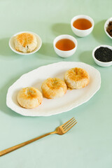 Traditional Chinese Mooncakes with Tea - Delicious Puff Pastry Asian Desserts on Green Background