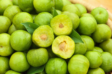 Fresh Green Plums Cut in Half Showing Flesh and Pits with Natural Leaves