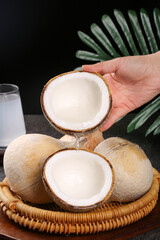 Fresh Coconuts with Coconut Milk Pouring from Shell - Tropical Fruit Arrangement with Palm Leaves