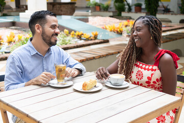 Happy couple enjoying drinks and pastry at outdoor cafe