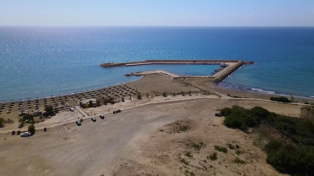 Aerial view of Durr&euml;s beachfront, Albania&mdash;sunbeds line the sandy shore beside a multi-armed pier extending into calm blue waters. A serene, structured coastal scene ideal for tourism themes.