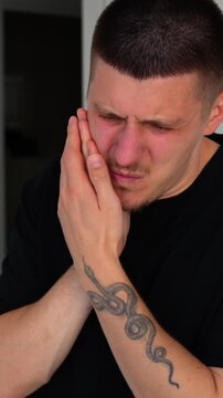 A man holds his cheek with his hand, showing severe toothache.
A man hides because of severe toothache.
Problems with caries and treatment of periodontosis