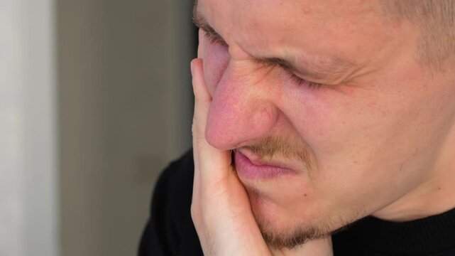 A man holds his cheek with his hand, showing severe toothache.
A man hides because of severe toothache.
Problems with caries and treatment of periodontosis