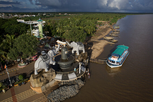 Aerial view of striking elephant statues guarding the shore near a docked boat, with a lush green landscape stretching towards the horizon, Rajahmundry, Andhra Pradesh, India.