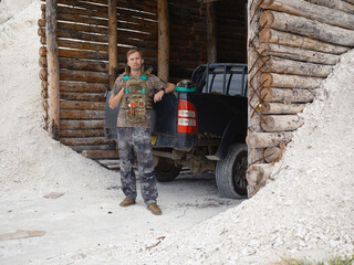 Fototapeta premium Ukrainian soldier standing near a dugout with car.