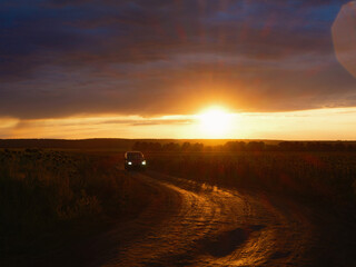 Car Driving on a Field Road at Sunset