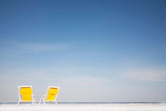 Two yellow deckchairs on beach