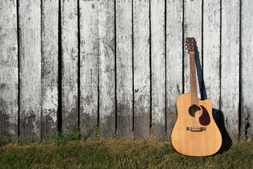 Acoustic guitar leaning against old barn wall