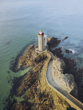 Aerial view of the Petit Minou lighthouse standing tall against the turquoise sea, connected by a winding causeway over rugged rocks, Pointe du Minou, Plouzan&Atilde;&copy;, Finist&Atilde;&uml;re, France.