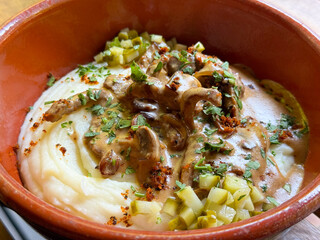 Traditional meat with mashed potatoes served in a clay bowl close-up. Comfort, taste, and cultural richness of homemade cuisine.