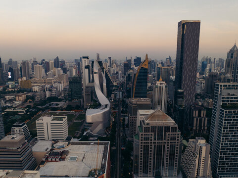 Fototapeta Aerial view of the cityscape reveals modern architecture and skyscrapers piercing the skyline, bathed in the soft glow of the setting sun, Bangkok, Bangkok, Thailand.