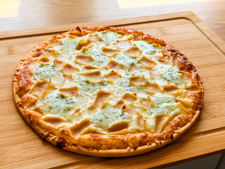 Whole baked pizza with cheese and toppings on wooden board. Food, leisure and culinary lifestyle in homemade dining culture.