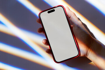 Close-up of woman's hand holding smart phone on light streaked background