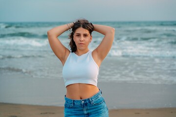 Young woman posing with hands in hair on the beach