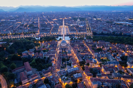 Aerial view of a city lit up at dusk, highlighting the grandeur of the Gran Madre di Dio church and the Po River, Turin, Piedmont, Italy.