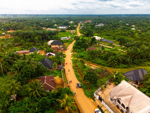 Aerial view of a road cutting through lush green vegetation, with buildings dotted around, creating a blend of nature and habitation, Amaolu Community, Imo State, Nigeria