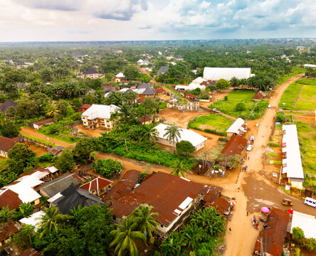 Aerial view of red-roofed buildings nestled amidst lush greenery, punctuated by roads and open spaces, creating a vibrant contrast under the cloudy sky, Amaolu Community, Imo State,, Nigeria.