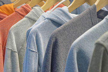 Personal wardrobe or shop window, group of hoodies and sweatshirts of different colors on hangers