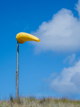 Yellow wind sock blowing in strong wind against sky