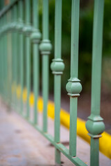 Close-up of green metal railing with decorative elements.