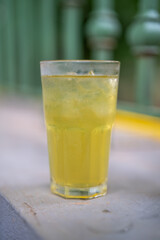Refreshing yellow beverage served in a glass with ice on a sunny day.