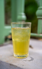 Refreshing yellow drink with ice in a clear glass.
