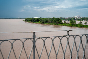 A scenic view of a river with lush greenery under a cloudy sky.