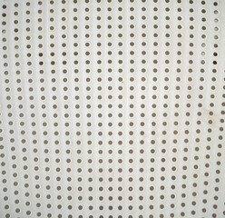 Close-up of a perforated white surface with uniform holes.