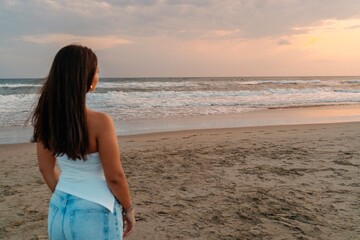 Woman looking at the sea during sunset on the beach