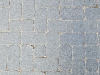 Gray cobblestone pavement texture. Top view of a timeless stone block path or road, a perfect rustic and durable background for design and architectural projects.