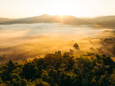 Aerial view of the sun illuminating the fog-laden valley and the Phu Langka Forest Park, Pha Chang Noi, Thailand.