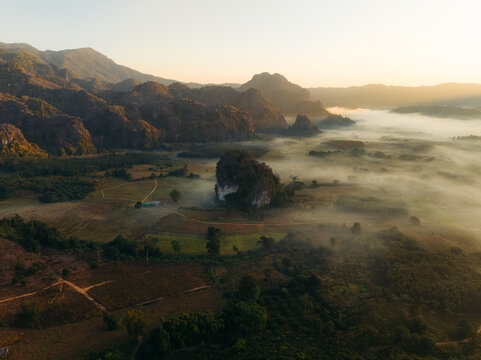 Aerial view of the sun's golden light kissing misty valleys and jagged peaks, a serene landscape unfolds in nature's embrace, Phu Langka Forest Park, Pha Chang Noi, Thailand.