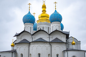 Orthodox church domes with gold and blue under cloudy sky