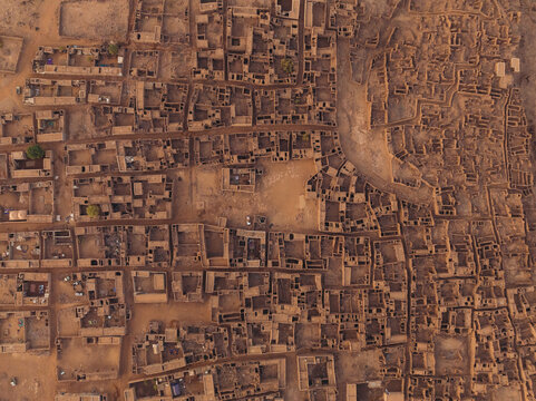Aerial view of a tapestry of tightly packed, sun-baked mud-brick structures and buildings form a maze-like settlement in the ancient city, Ouadane, Adrar, Mauritania.