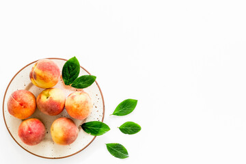 Summer fruits. Ripe red peaches on plate on white table top-down copy space
