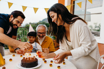Family celebrating a birthday outdoors with cake and decorations