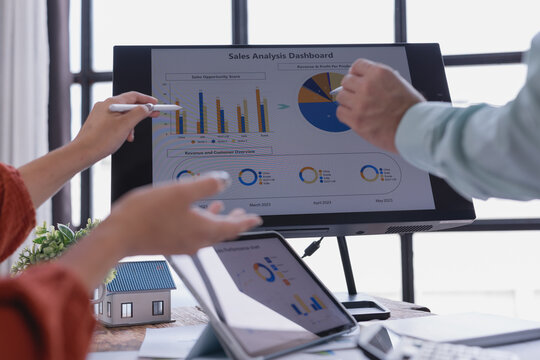Business colleagues discussing sales performance using data visualization tools on a computer screen and tablet, enhancing their strategic decision-making process