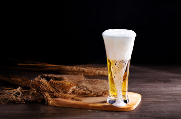 Ready-to-drink draft beer in a glass with white foam, alcoholic beverage, placed on a wooden table for dinner.