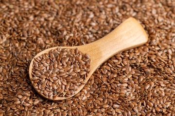 flax seeds for sowing in a wooden spoon, a large number of light brown flax seeds and a wooden spoon with seeds