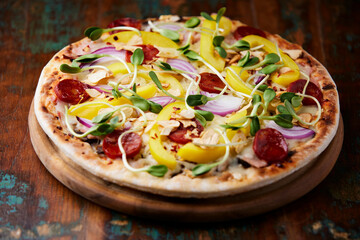Pizza with chorizo ​​sausage, mozzarella cheese and yellow pepper. Rustic wooden background. Soft focus.
