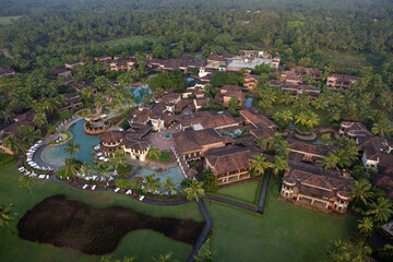 Bambolim, India - 16 November 2013: Aerial view of terracotta roofs contrasting with the bright turquoise pools, nestled amidst the verdant canopy of Goa's tropical foliage.