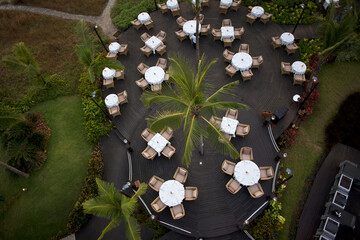 Bambolim, India - 17 November 2013: Aerial view of a circular outdoor dining area, tables draped in white linen nestled amidst lush greenery and palm trees.